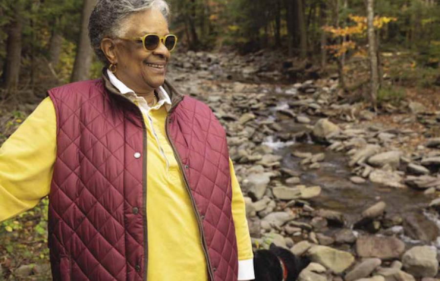 woman with sunglasses stands in front of a creek