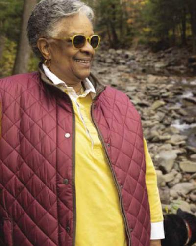 woman with sunglasses stands in front of a creek